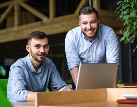 Picture of handsome businessman listening to his colleague or partner concerning ner business system while working on laptop computer in office interior.